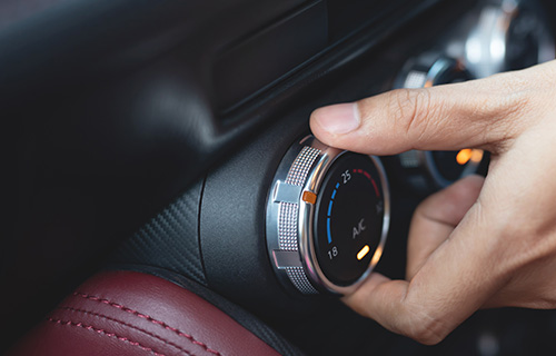 close up of hand turning air con dial in car